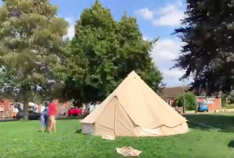 A 6 m Bell Tent pitched on grass in the UK surrounded by blue sky and trees